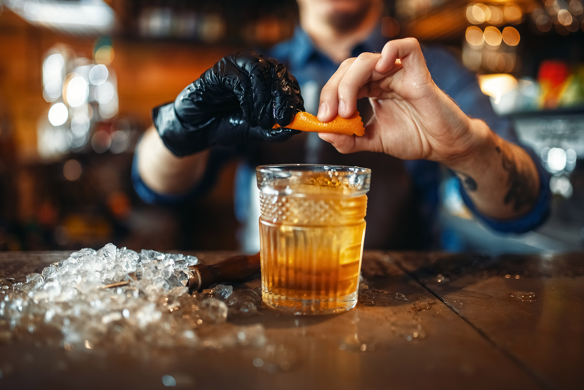 Barman wyciskający skórkę pomarańczy, ilustracja do artykułu o old fashioned